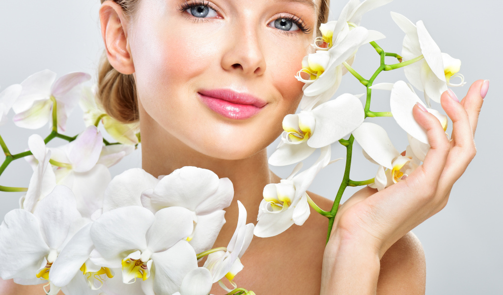Нежная голубоглазая девушка с цветами орхидеи в руках