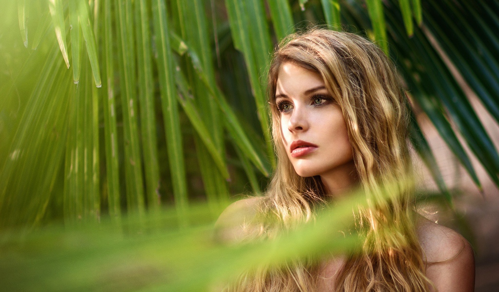Девушка с волнистыми волосами в пальмовых листьях 