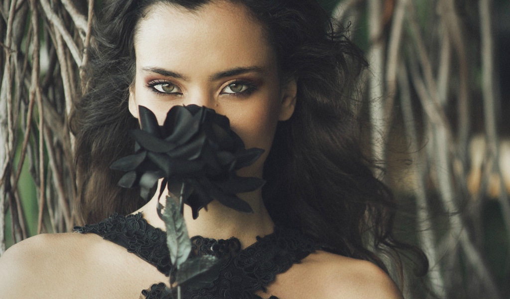 Зеленоглазая девушка брюнетка с черной розой в руках