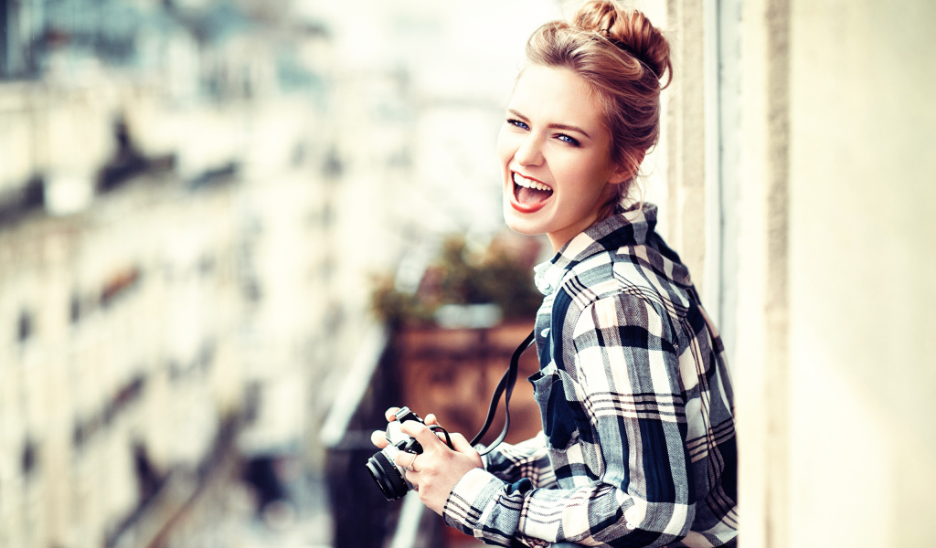 Улыбающаяся девушка в клетчатой рубашке с фотоаппаратом 