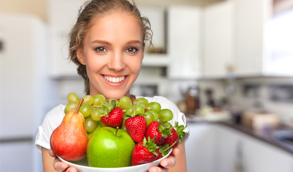 Улыбающаяся девушка со свежими фруктами 