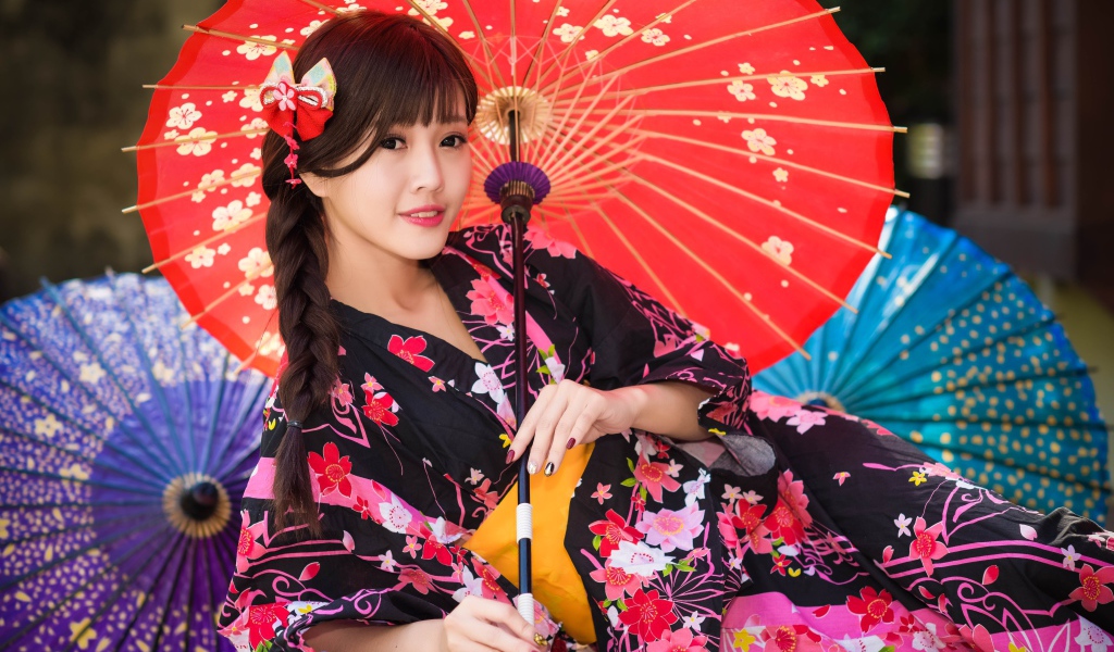 Молодая азиатка в кимоно с разноцветными зонтиками
