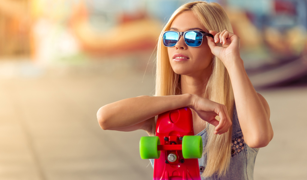 Молодая блондинка в солнечный очках со скейтбордом