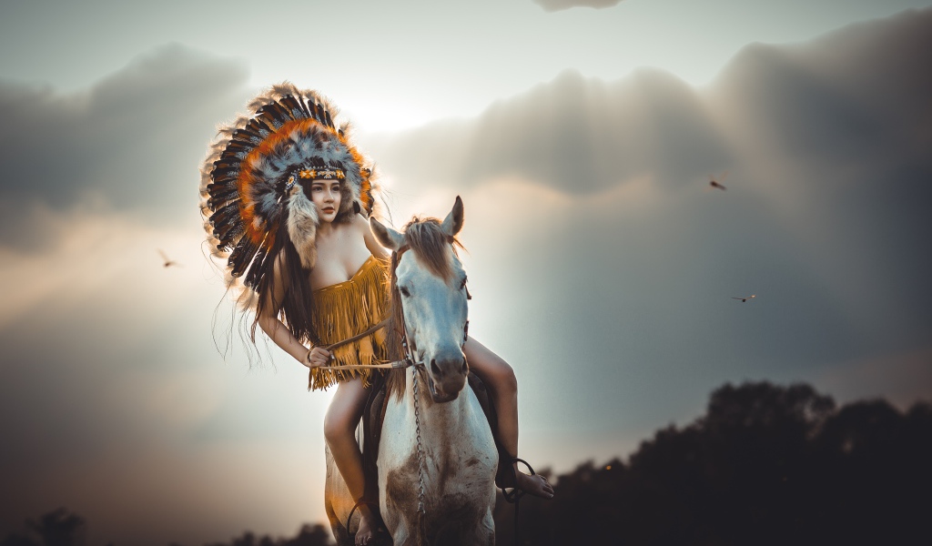 Молодая девушка в костюме индейца на коне