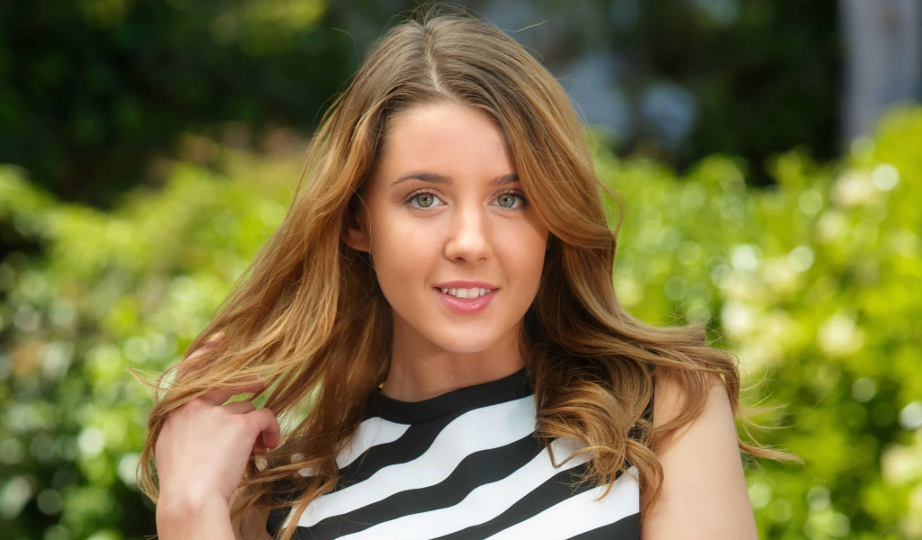 Молодая улыбающаяся девушка в полосатом платье