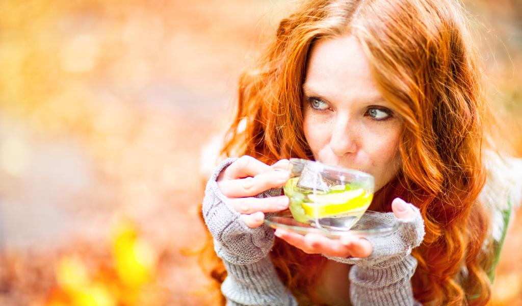 Рыжеволосая девушка модель с чашкой зеленого чая 
