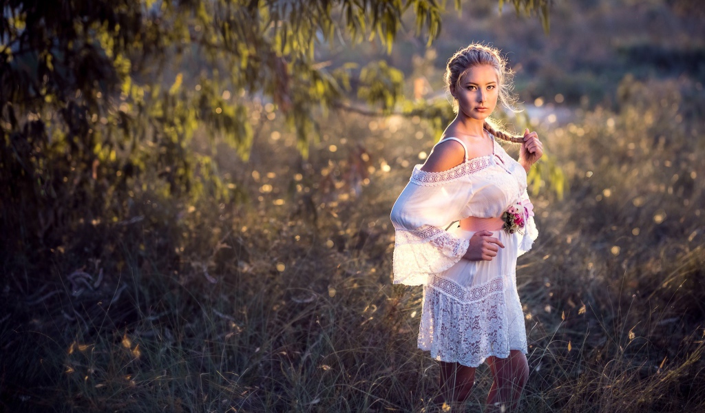 Молодая девушка модель в красивом белом платье с косой на голове