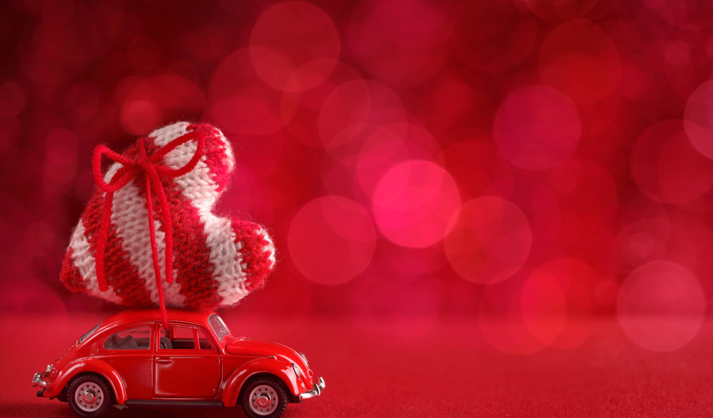 Красная игрушечная машинка везет с сердечко на розовом фоне, фон для открытки на День Святого Валентина