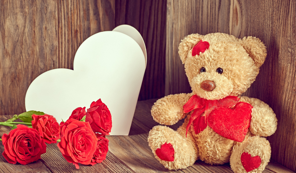 Плюшевый медведь с большим белым бумажным сердцем и красными розами
