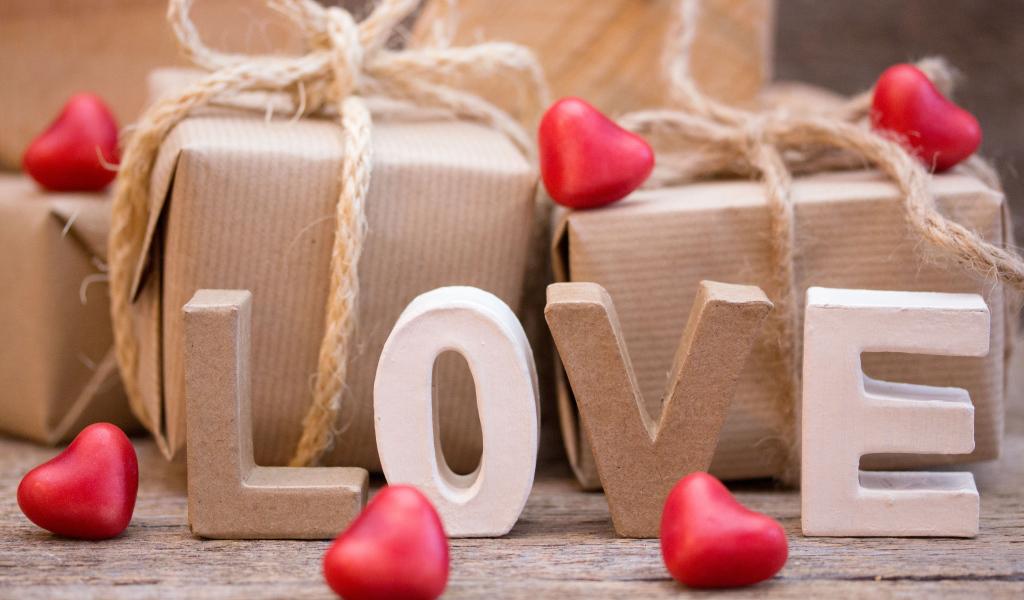 Романтические подарки и надпись Love с красными сердечками