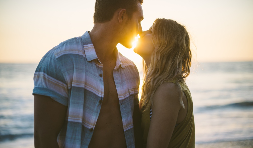 Романтический поцелуй влюбленной пары на закате солнца