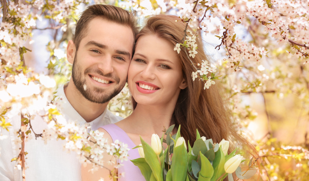 Улыбающаяся влюбленная пара у цветущего дерева