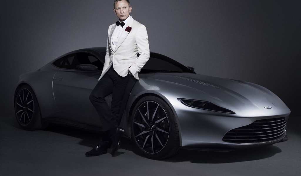 Знаменитый актер Дэниел Крэйг рядом с серебристым автомобилем Aston Martin