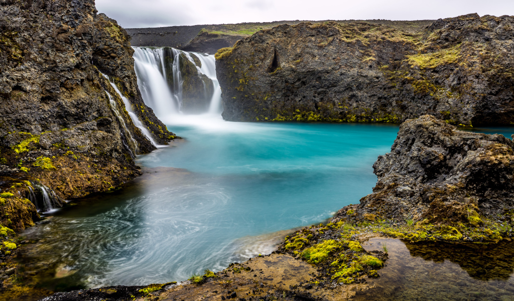 Красивый водопад между скалистых берегов 