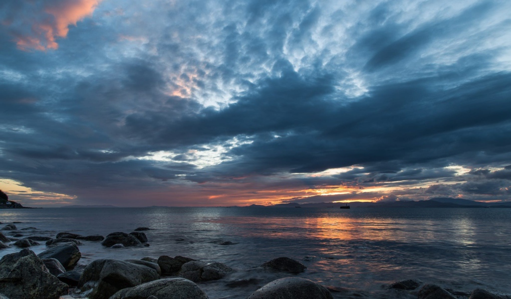 Валуны в воде на берегу на фоне пасмурного неба 