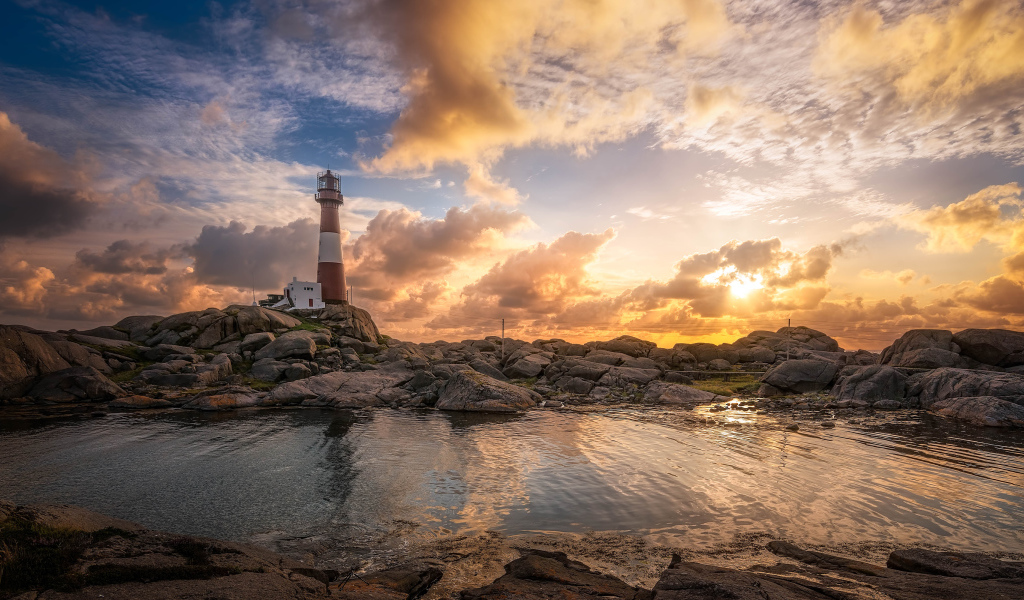 Маяк на каменном побережье на фоне красивого неба