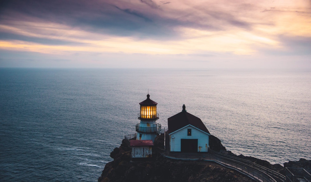 Маяк на скале на фоне горизонта океана 