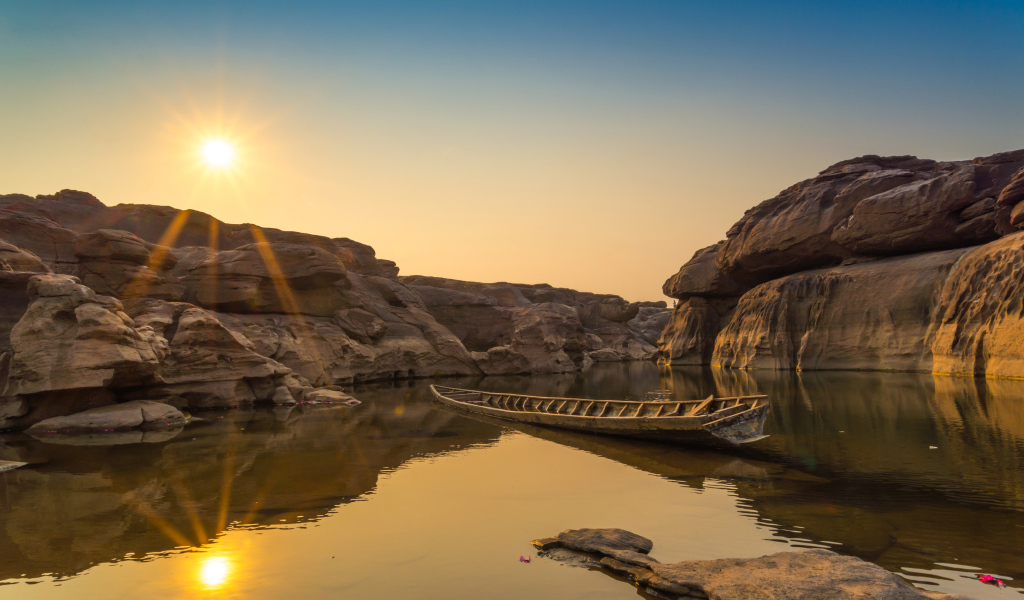 Лодна на озере между скал на рассвете