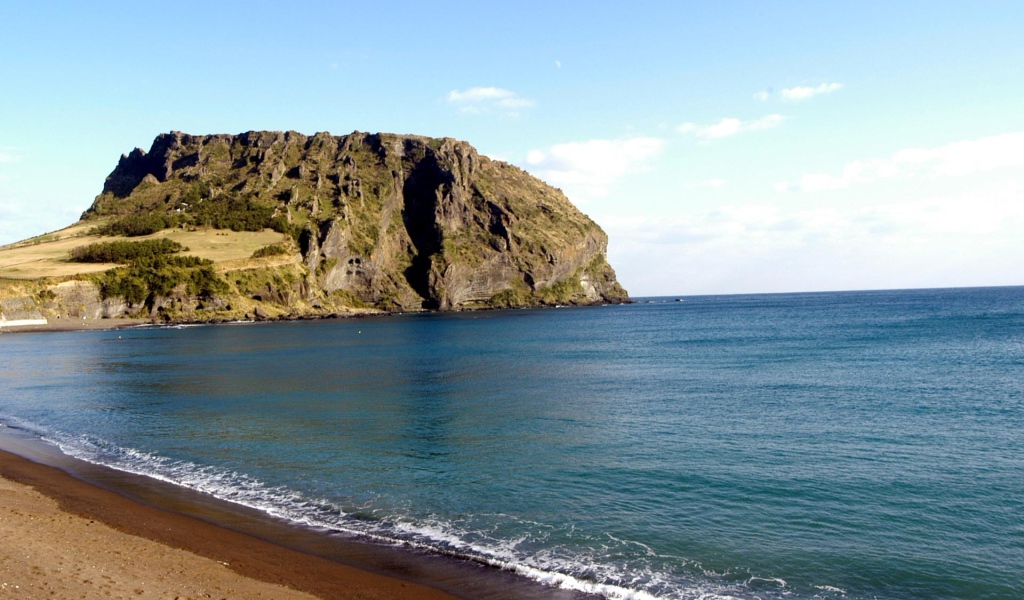 Гора на фоне спокойной воды моря под голубым небом