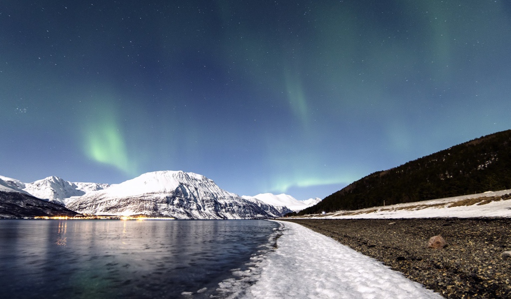 Северное сияние в небе над заснеженными горами 