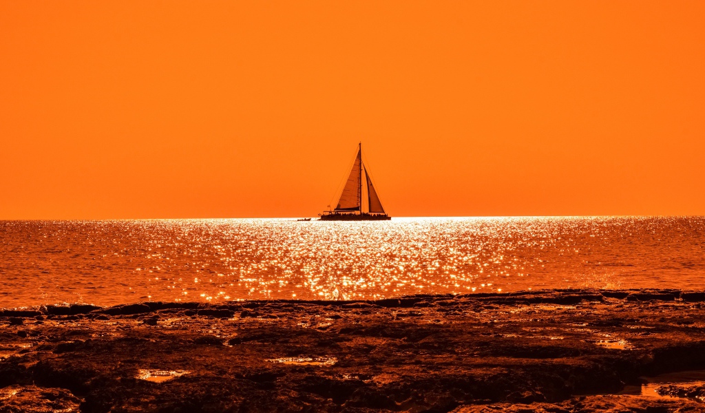 Парусная лодка на горизонте в океане на закате солнца