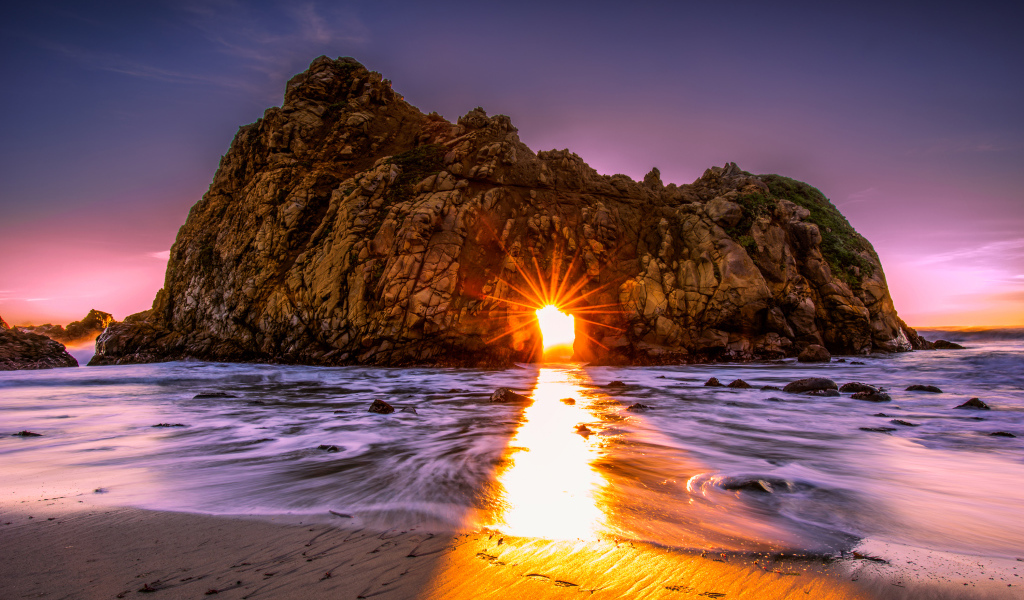 Лучи солнца пробиваются сквозь отверстие в скале  Pfeiffer Beach Big Sur, Калифорния  