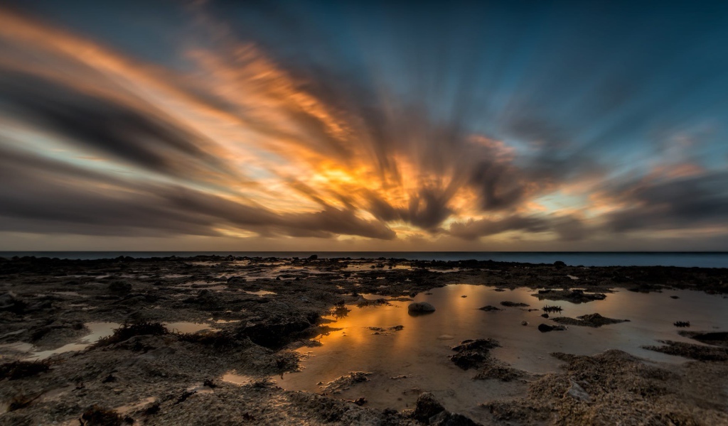 Закат солнца в облаках над водой 