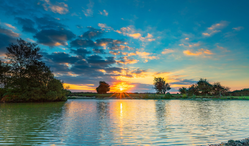 Закат солнца в небе отражается в воде озера 