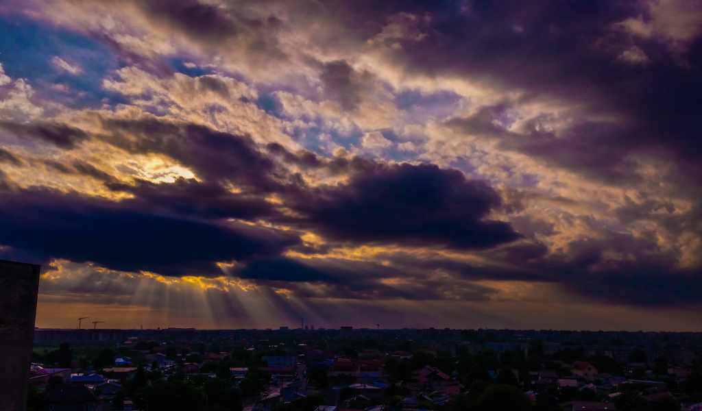 Лучи солнца пробиваются сквозь облака над городом