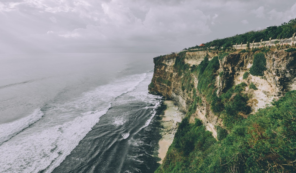 Бушующие волны у зеленого утеса 