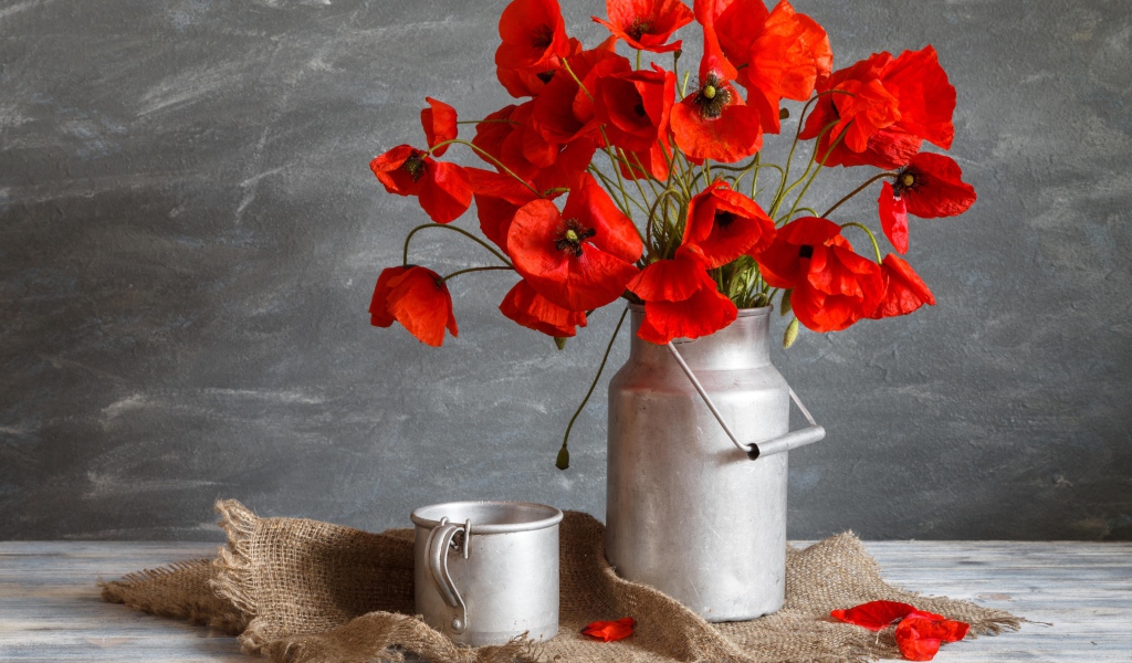 Букет красных маков в железном бидоне на столе с кружкой