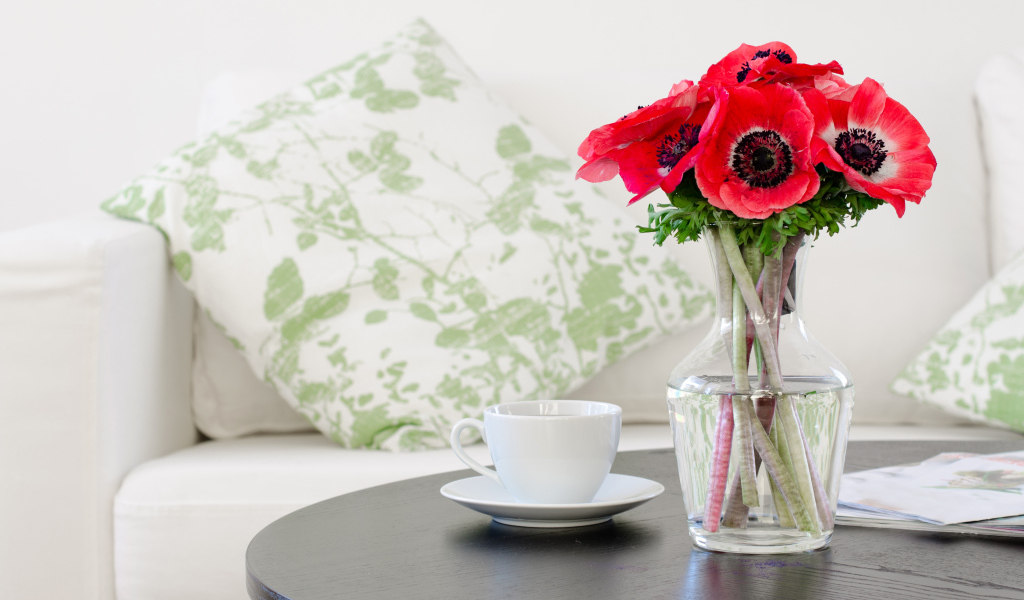 Букет красных цветов анемоны в вазе на столе с белой чашкой