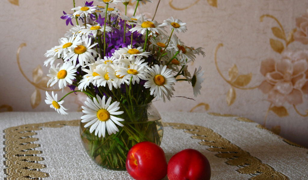 Букет белых полевых ромашек в вазе на столе с розовыми персиками