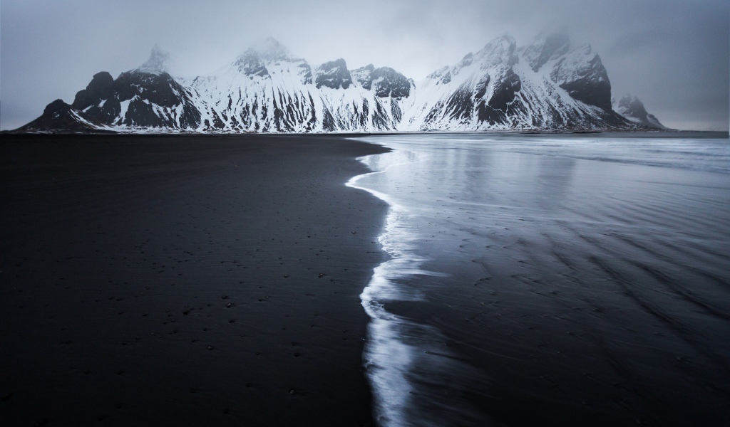 Заснеженные горы у пустынного пляжа