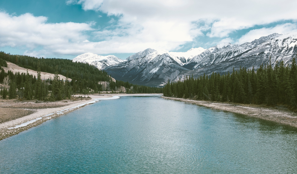 Чистая голубая вода в реке на фоне заснеженных гор 