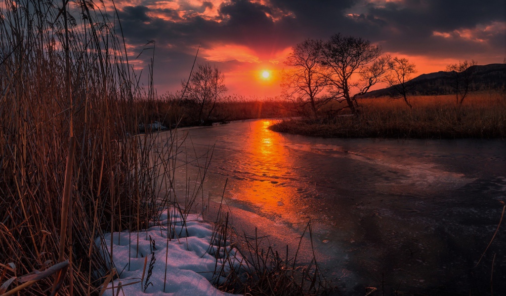 Закат солнца над покрытой льдом рекой