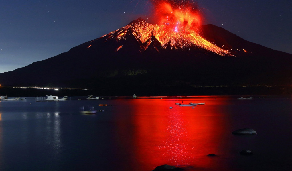 Вулкан Сакурадзима извергается  на фоне воды 