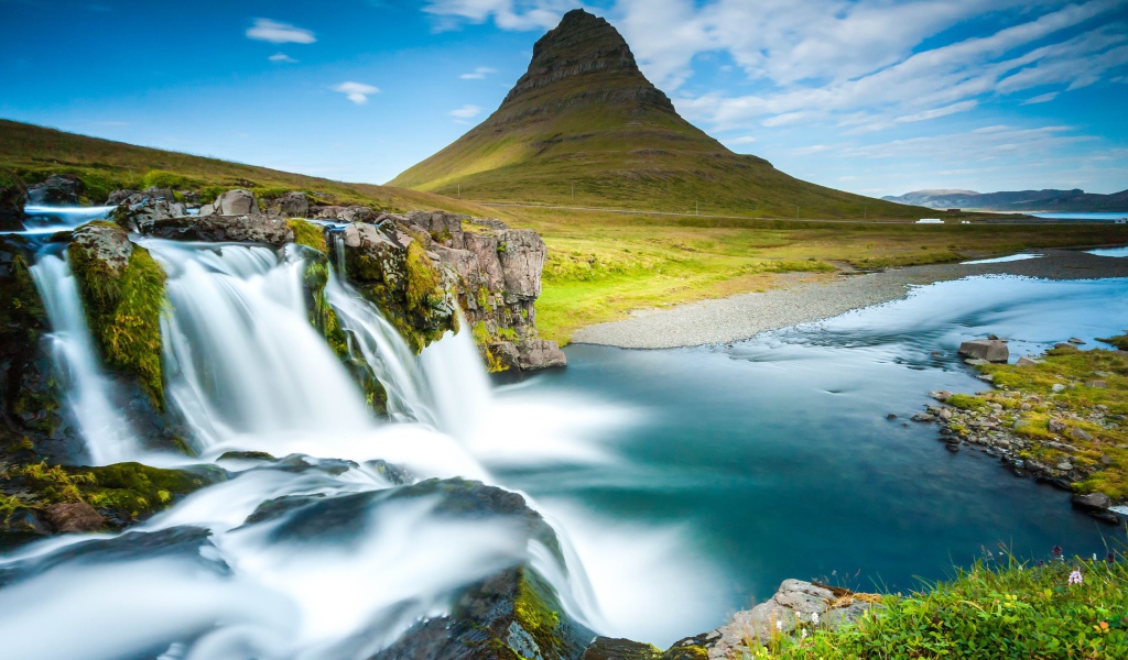 Водопад стекает в реку на фоне горы под красивым небом