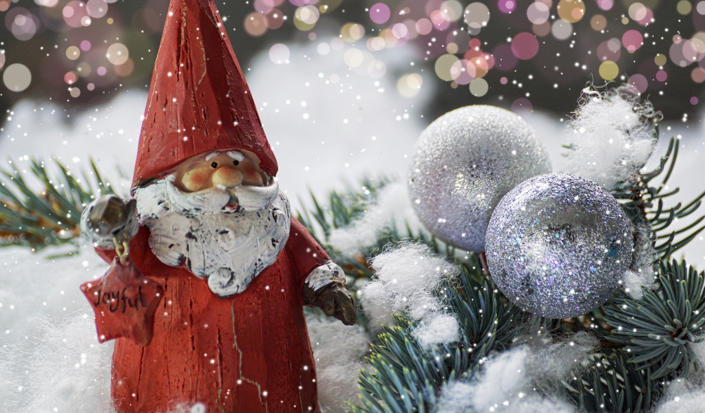 Статуэтка деда Мороза рядом с еловой веткой и яркими шарами