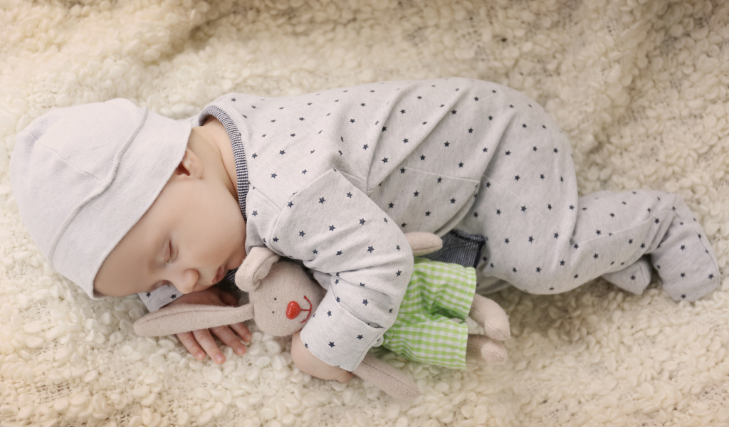 Грудной ребенок спит с любимой мягкой игрушкой
