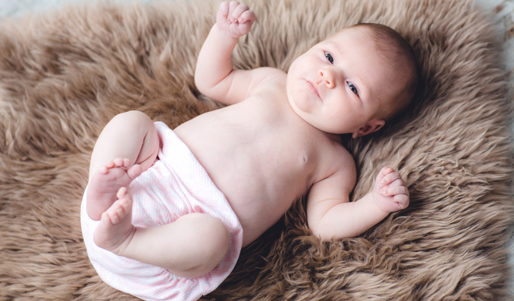 Грудной ребенок лежит на меховом покрывале