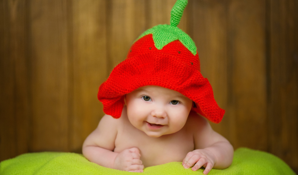 Младенец в забавной шапке клубнике на голове