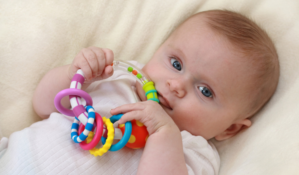 Грудной ребенок с погремушкой в руках