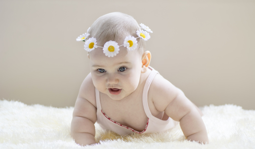 Грудной ребенок с венком из белых ромашек на голове