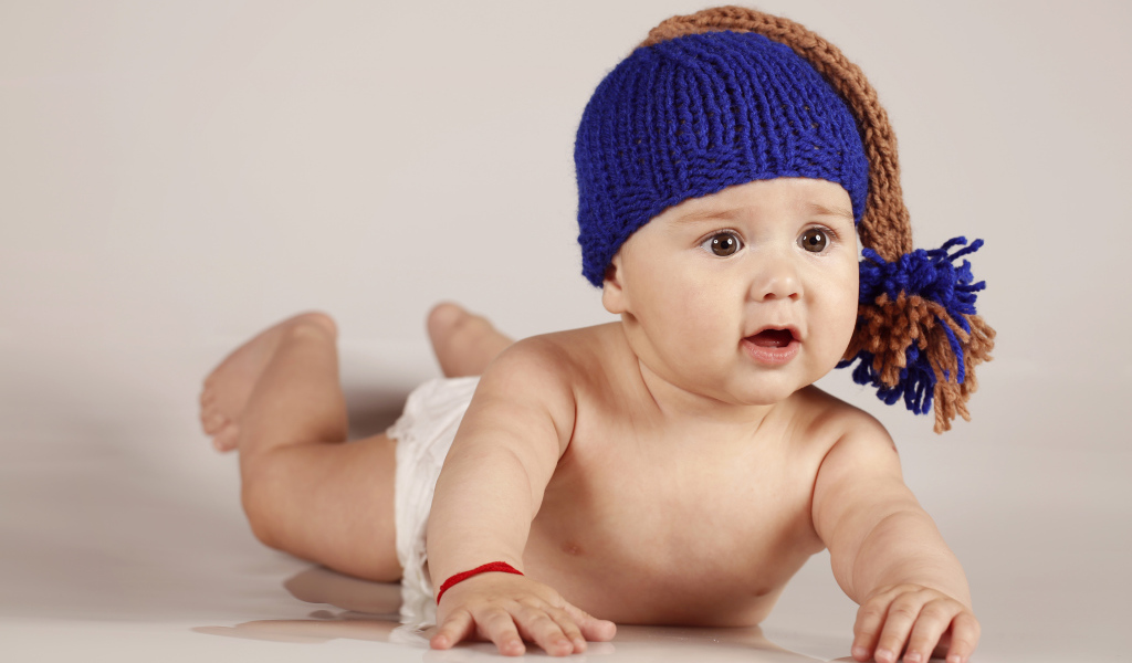 Грудной кареглазый ребенок в вязаной шерстяной шапке