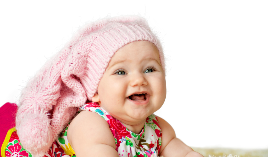 Милая маленькая улыбающаяся девочка в большой розовой шапке