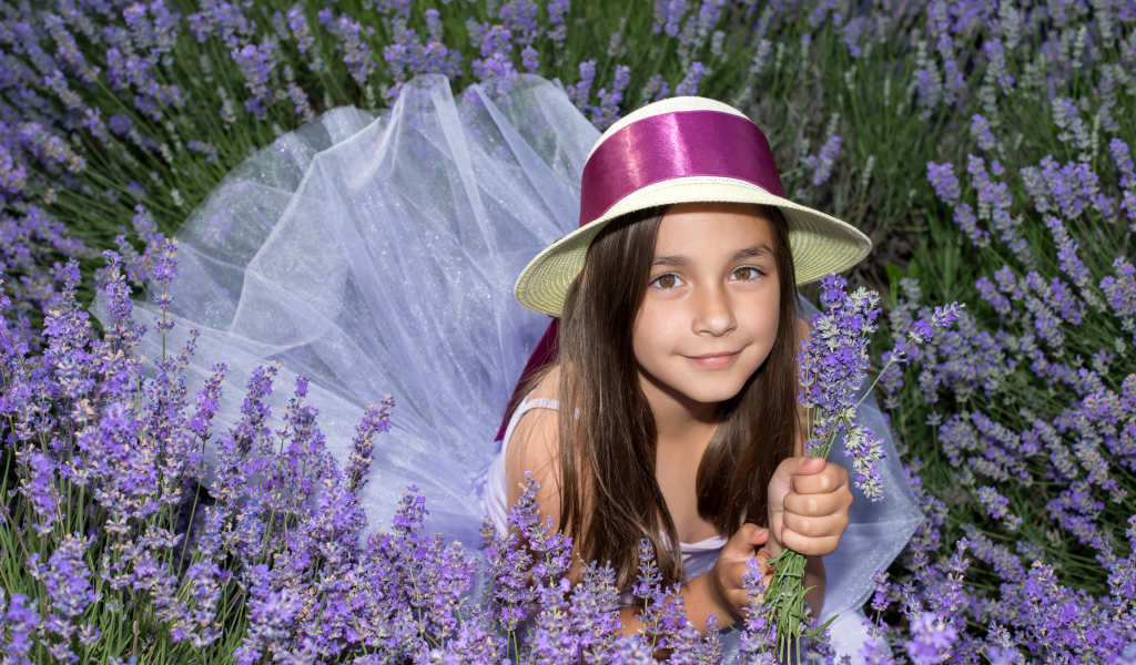 Девочка в шляпе лежит в фиолетовых цветах лаванды