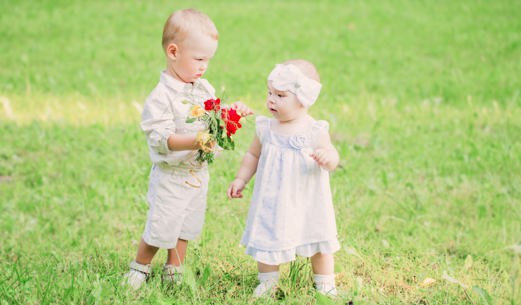 Маленький мальчик дарит букет полевых цветов девочке