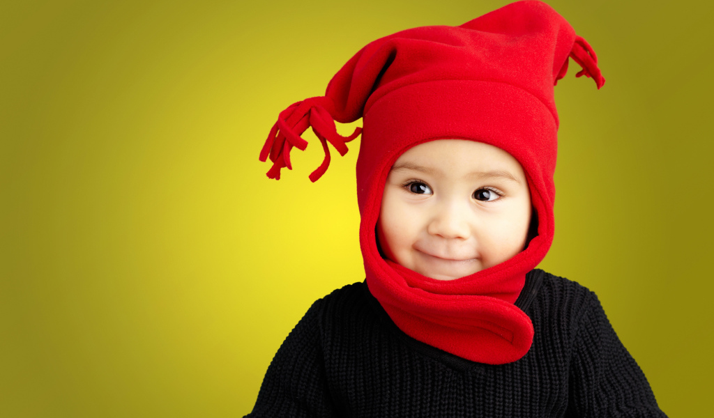 Маленький мальчик в красной шапке и в черном свитере