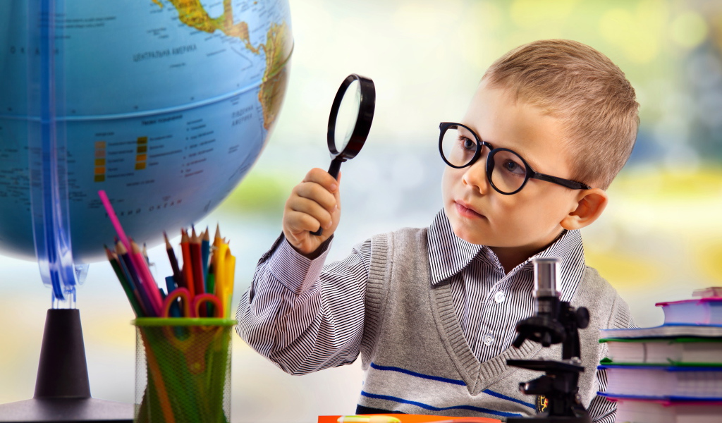 Маленький мальчик в очках исследует глобус